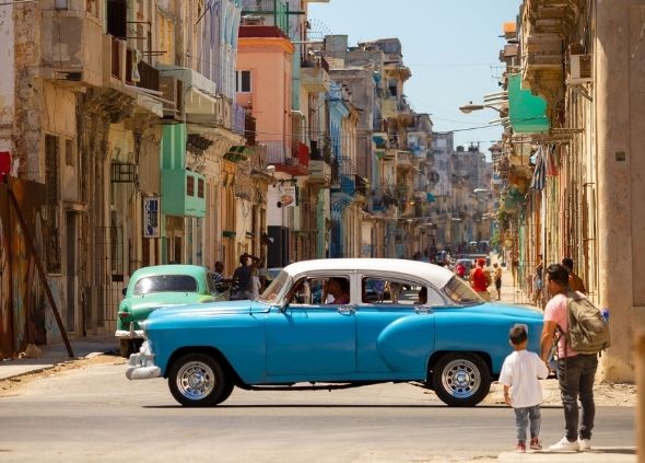 Man helping little boy cross the road on a street in Havana